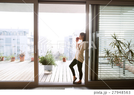 Woman relaxing on balcony holding cup of coffee or Woman relaxing on balcony holding cup of coffee or 27948563