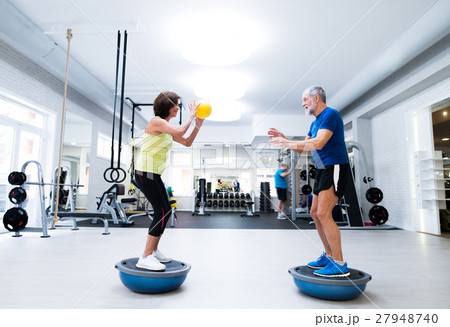 Senior couple in gym working out with weights Senior couple in gym working out with weights 27948740