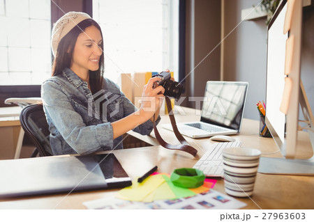 Graphic designer looking at pictures in digital camera 27963603