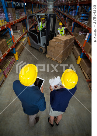 High angle view of manager wearing hard hat and looking workers High angle view of manager wearing hard hat and looking workers 27964258