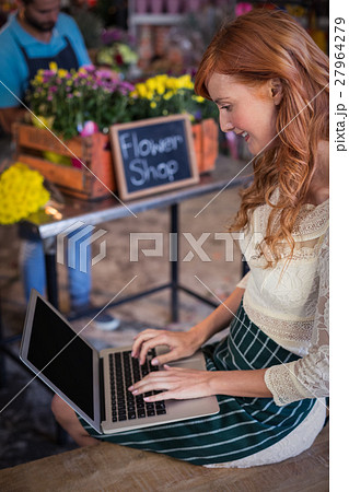 Female florist sitting and using laptop Female florist sitting and using laptop 27964279