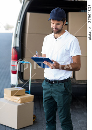 Portrait of delivery man is writing something on a clipboard Portrait of delivery man is writing something on a clipboard 27964338