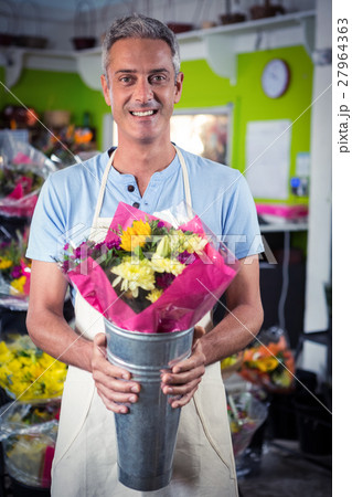 Male florist holding flower bouquet at flower shop 27964363
