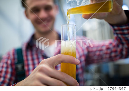 Brewer pouring beer in hydrometer cylinder Brewer pouring beer in hydrometer cylinder 27964367