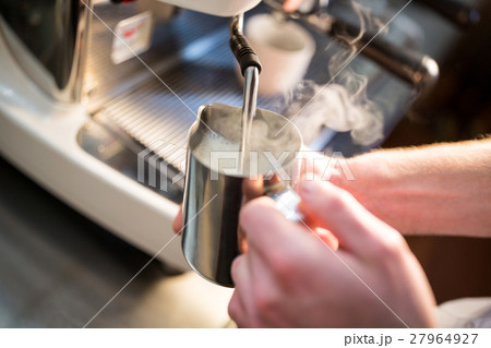 Waiter steaming milk at the coffee machine Waiter steaming milk at the coffee machine 27964927