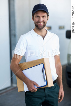 Portrait of delivery man is holding cardboard box and posing 27965046