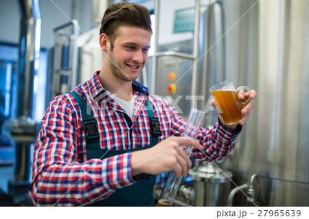 Brewer pouring beer in hydrometer cylinder 27965639