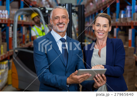 Portrait of happy managers holding a tablet and looking the camera Portrait of happy managers holding a tablet and looking the camera 27965640