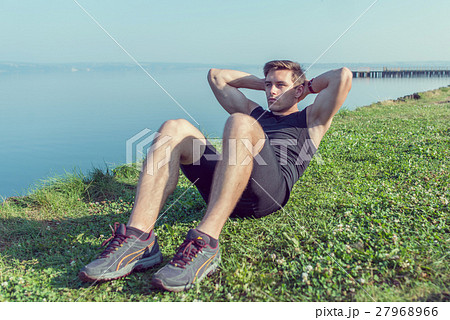 Sporty young man doing sit-ups abs crunches Sporty young man doing sit-ups abs crunches 27968966