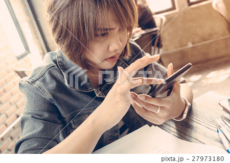 Asian girl concentrating at her smart phone Asian girl concentrating at her smart phone 27973180