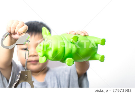 Asian boy holding piggy bank and handcuff. Asian boy holding piggy bank and handcuff. 27973982