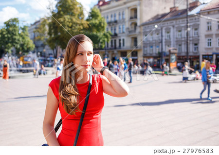 Young woman in red dress walking on street 27976583