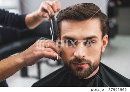 Skillful hairdresser cutting male hair Skillful hairdresser cutting male hair 27995966