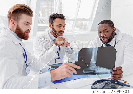 Confident three doctors analyzing x-ray photo Confident three doctors analyzing x-ray photo 27996381