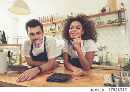 Two outgoing baristas standing at counter in cozy 27998537