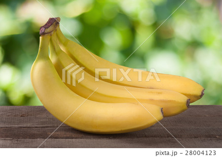 Three bananas on a wooden board with blurred 28004123