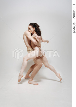 Muscular young athletes posing against white Muscular young athletes posing against white 28005981