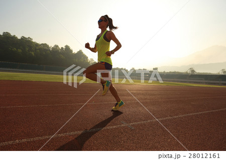 young woman runner running on stadium track 28012161