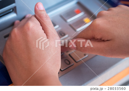hand entering PIN pass code on ATM 28033560