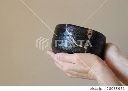 金継された抹茶茶碗を持つ（横位置） 28033921