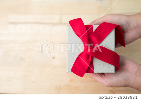 Gift box with red ribbon on wooden table Gift box with red ribbon on wooden table 28033931