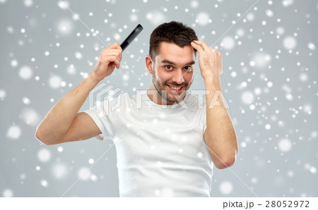 happy man brushing hair with comb over snow 28052972