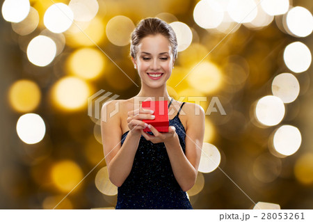 smiling woman holding red gift box over lights 28053261