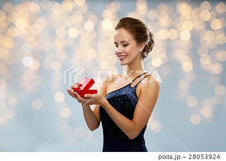 smiling woman holding red gift box over lights smiling woman holding red gift box over lights 28053924