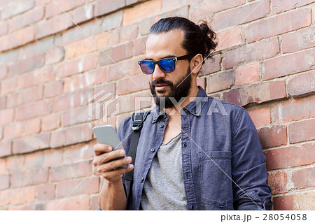 man with backpack texting on smartphone in city 28054058