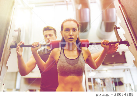 man and woman with barbell flexing muscles in gym 28054289