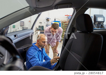 mechanic and man checking seat belt at car shop mechanic and man checking seat belt at car shop 28054817