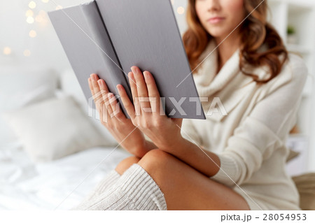 close up of young woman reading book at home close up of young woman reading book at home 28054953