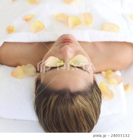 Mid adult woman lying on back under sheet covered with rose petals 28055132
