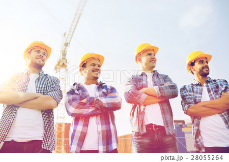 group of smiling builders in hardhats outdoors 28055264