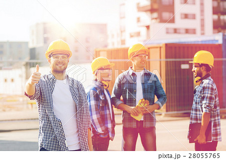 group of smiling builders in hardhats outdoors group of smiling builders in hardhats outdoors 28055765