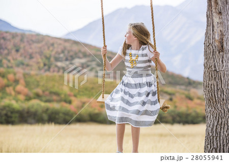 Girl (8-9) sitting on swing 28055941