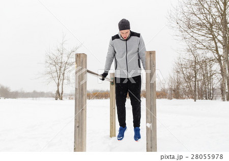 young man exercising on parallel bars in winter 28055978
