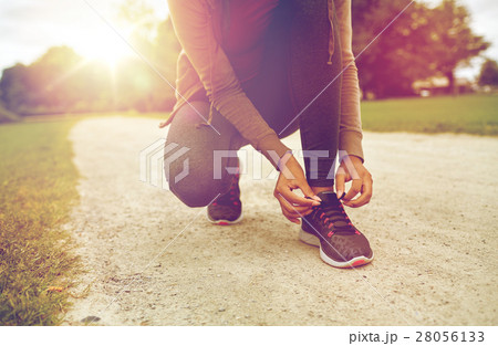 close up of woman tying shoelaces outdoors 28056133