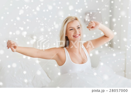 young woman stretching in bed after waking up young woman stretching in bed after waking up 28057000