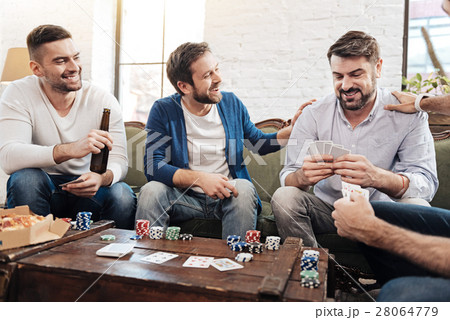 Delighted bearded man looking at his cards Delighted bearded man looking at his cards 28064779