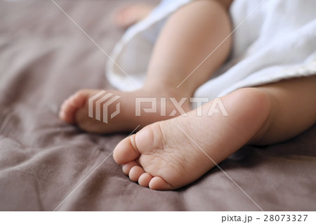 茶色のシーツのベットの上でお昼寝している幼児の小さくかわいい足 28073327