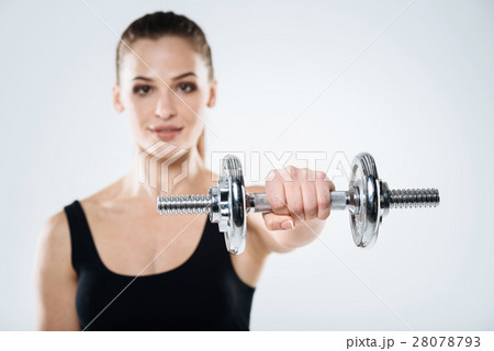 Motivated girl exercising with dumbbells on a grey 28078793