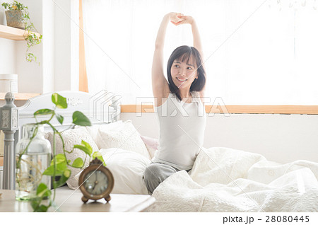 寝起きに伸びをする若い20代女性と目覚まし時計 28080445