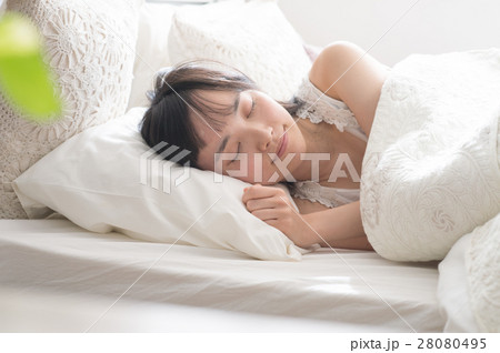 ベッドで眠る若い代女性の写真素材