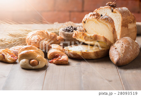 Assortment of baked bread and wheat on wood table Assortment of baked bread and wheat on wood table 28093519