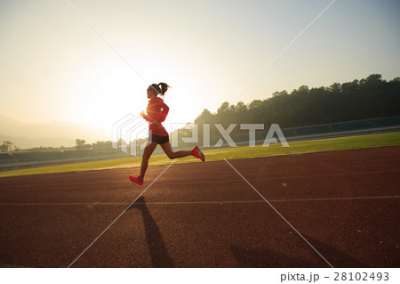 Young woman running during sunny morning on stadium track 28102493