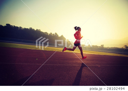 Young woman running during sunny morning on stadium track 28102494