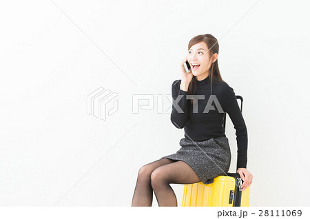 スーツケースに座る女性の写真素材
