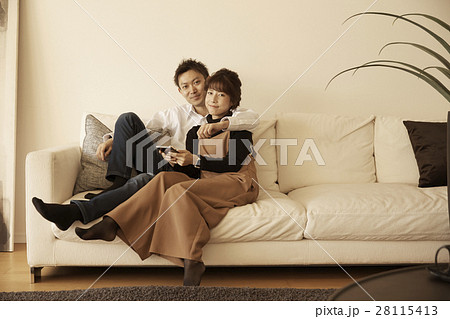 タワーマンション ソファでくつろぐカップルの写真素材