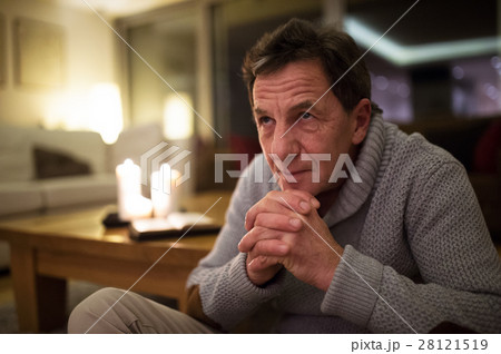Senior man at home praying, burning candles behind 28121519